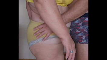 My wife, a voluptuous woman in her sixties, and I share a sultry kiss.