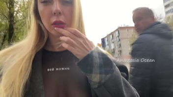 A gal exposes her breasts while walking in the city.